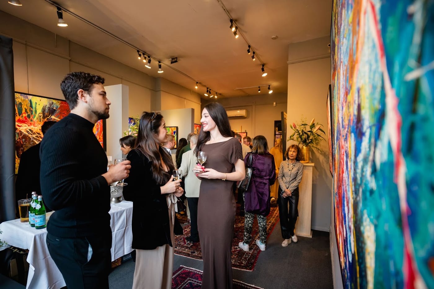 Guests with drinks at a private view in the gallery, talking in front of large abstract paintings